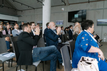 Menschen in Businesskleidung sitzen im Publikum und klatschen